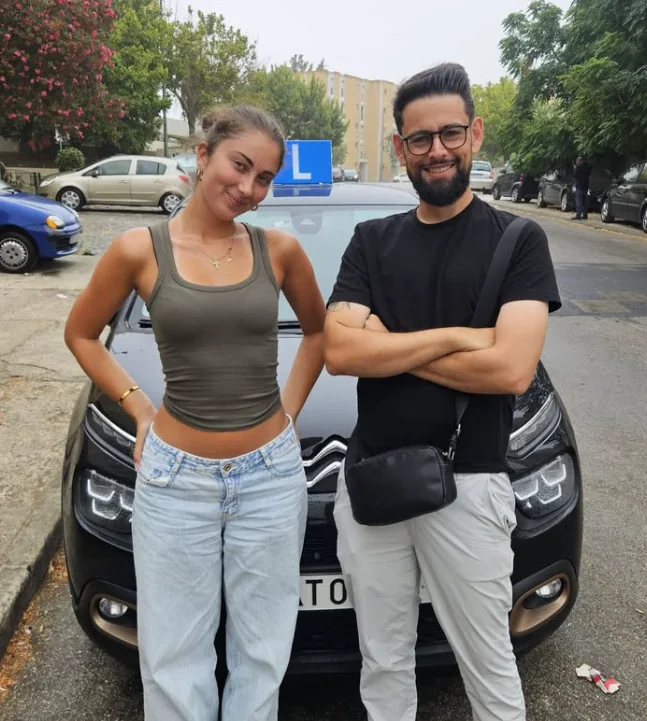 Aluna e instrutor junto ao carro da escola